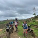 Family taking a break during Lombok dirt bike tour with scenic views.